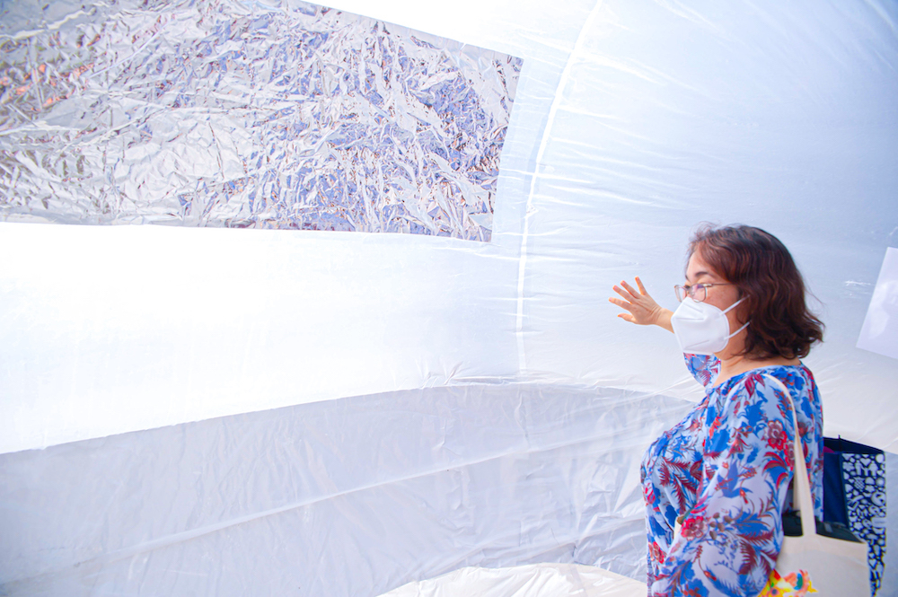 A woman inside the inflatable reaches her hand up to touch the side inner curving surface.