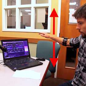 A person demonstrates wearing the Myo armband and moving their arm up and down while using the audio plugin we developed to change an audio parameter in the DJ software.