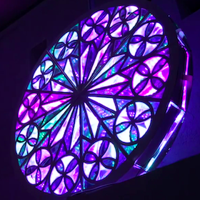 Glowing purple pillar and glowing purple, green, and white geometric decorative light fixture.