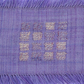 A close-up of purpose woven fabric with inlay in a pattern of a four by four grid of squares. Some of the squares are the same purple color as the background fabric, while others are white.